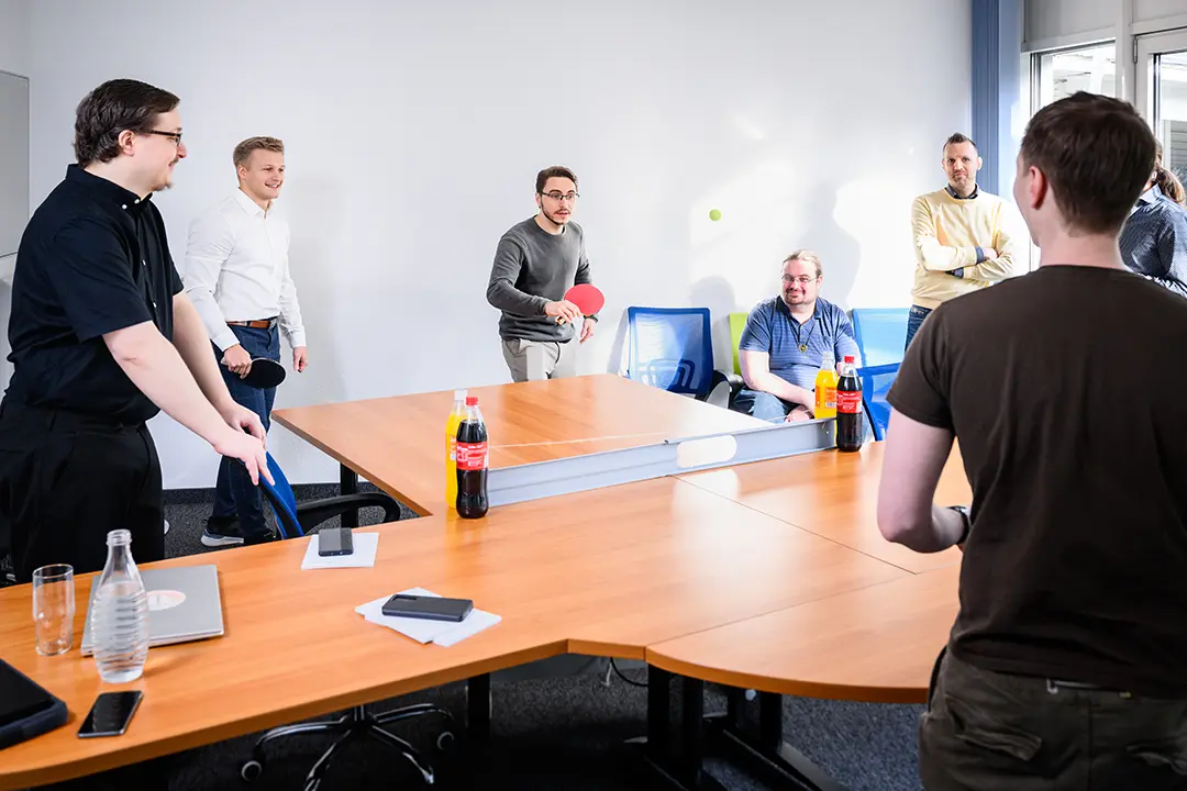 Kolleginnen und Kollegen spielen Tischtennis im Besprechungsraum.